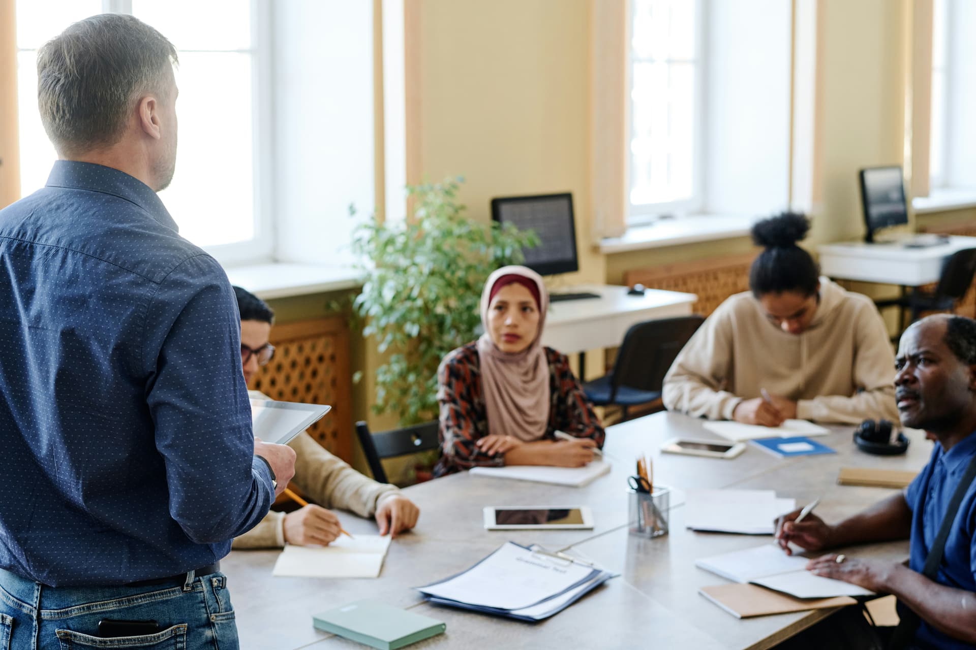 Teacher guiding adult ESL students through practical exercises